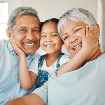 Grandparents smiling with grandchild in between them. Read about Beneficiary Designations Grandparents smiling with grandchild in between them. Read about Beneficiary Designations